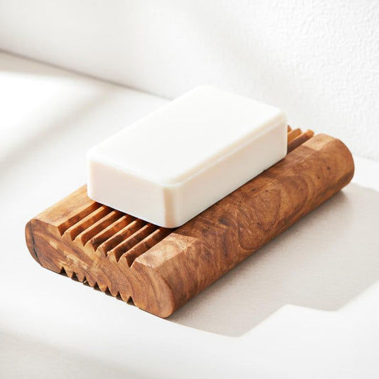 Handgefertigte Seifenschale aus Olivenholz mit weißer Seife auf hellem Badezimmerhintergrund