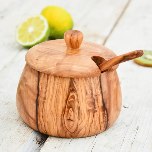 Salztopf aus Olivenholz mit Deckel und Holzlöffel auf hellem Untergrund