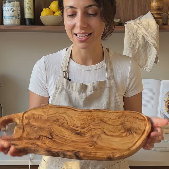 Handgefertigtes Charcuteriebrett aus Olivenholz mit geschnitztem Griff, Servierbrett mit Käse, Trauben und Brot, natürliches Unikat für Küche und stilvolle Tischpräsentation in der Schweiz