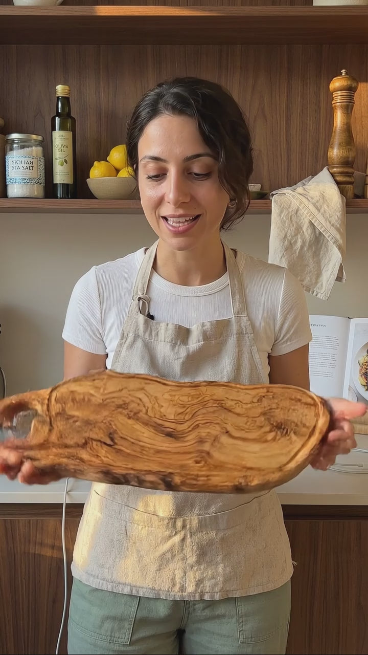 Handgefertigtes Charcuteriebrett aus Olivenholz mit geschnitztem Griff, Servierbrett mit Käse, Trauben und Brot, natürliches Unikat für Küche und stilvolle Tischpräsentation in der Schweiz